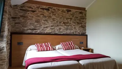 a bedroom with a large bed with red and white pillows at Pension Albergue Alborada in Salceda