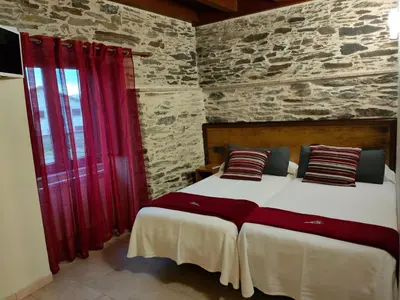 a bedroom with two beds and a stone wall at Pension Albergue Alborada in Salceda