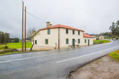 a white house on the side of a road at Pension Albergue Alborada in Salceda