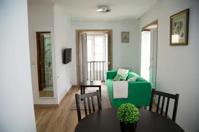 a living room with a green couch and a table at Xavestre Rooms Santiago in Santiago de Compostela
