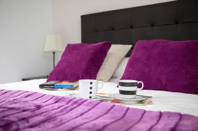 a bed with purple pillows and a table with two coffee cups at Xavestre Rooms Santiago in Santiago de Compostela