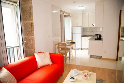a living room with a red couch and a kitchen at Xavestre Rooms Santiago in Santiago de Compostela
