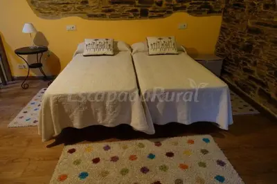 a bedroom with two beds and a rug at Casa Carballeira in Villarfernando