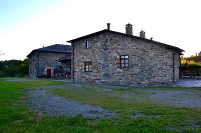 an old stone house with a grass field in front of it at Apartamentos Rurales RON in Ron