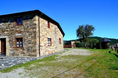 a large stone building with a grass yard next to it at Apartamentos Rurales RON in Ron