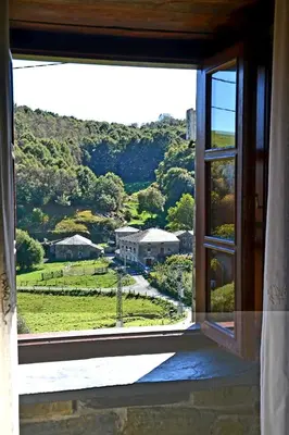 an open window with a view of a house at Apartamentos Rurales RON in Ron