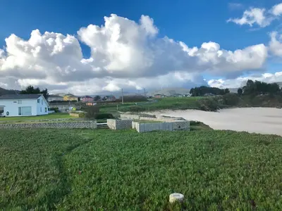 a field of grass with a river and a house at Apartagal- Casa Playa, Foz in Foz
