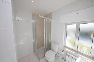 a white bathroom with a shower and a toilet at Apartagal- Casa Playa, Foz in Foz