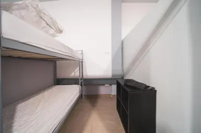 a bedroom with two bunk beds and a black cabinet at Albergue Barullo - Cubículos - Literas - Habitaciones in Sarria