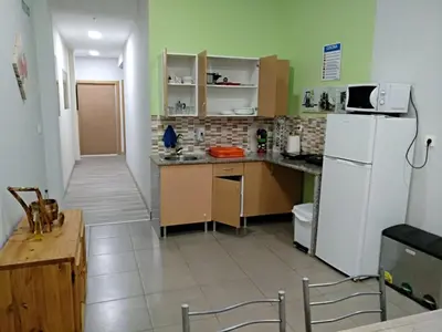 a kitchen with a white refrigerator and a table at Albergue Barullo - Cubículos - Literas - Habitaciones in Sarria