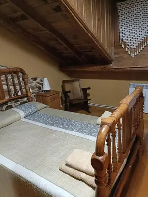 a bedroom with a wooden bed and a chair at Casa do Eiró in Lago de Carucedo