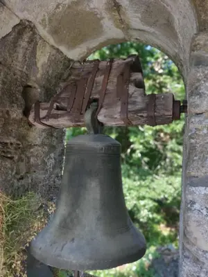 an old bell sitting under a stone archway at Apartamentos Turísticos Cabrera in Tejedo de Ancares