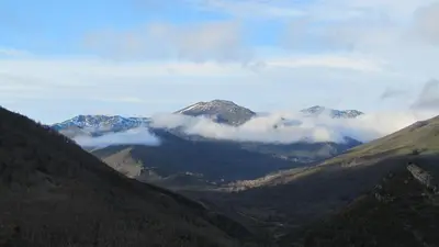 a view of a mountain range with clouds in the valley at Apartamentos Turísticos Cabrera in Tejedo de Ancares