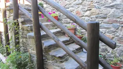 a set of wooden stairs with a stone wall at Apartamentos Turísticos Cabrera in Tejedo de Ancares