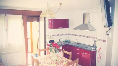 a kitchen with a table with a vase of flowers on it at Apartamentos Turísticos Cabrera in Tejedo de Ancares