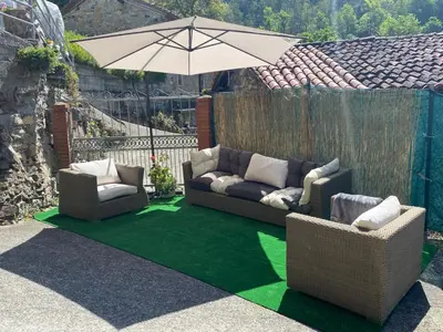 a patio with two couches and an umbrella at Casa Rural La Corrada in Llamoso