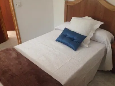 a white bed with a blue pillow on it at Casa Rural La Corrada in Llamoso