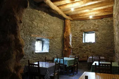 a dining room with tables and chairs in a stone wall at El Rincón del Cuco in Tejedo de Ancares