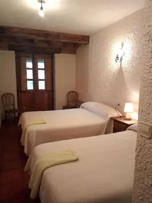 a room with four beds and a table with a lamp at El Rincón del Cuco in Tejedo de Ancares