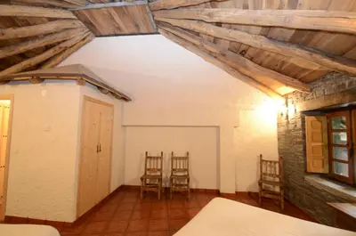 a room with chairs and wooden ceilings and a door at El Rincón del Cuco in Tejedo de Ancares