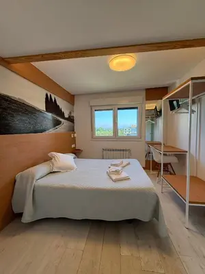 a bedroom with a large bed and a desk at Pension Restaurante Casa Camiño in Palas de Rei