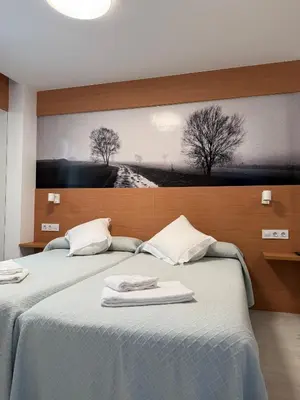 two beds in a room with a painting on the wall at Pension Restaurante Casa Camiño in Palas de Rei