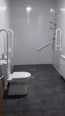 a white bathroom with a toilet and a sink at Albergue O Trisquel in O Pedrouzo