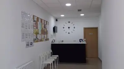 a waiting room with a clock on the wall and chairs at Albergue O Trisquel in O Pedrouzo