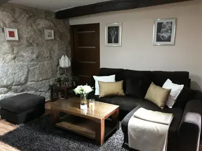 a living room with a black couch and a table at Casa da Xeitosa in Barbudo