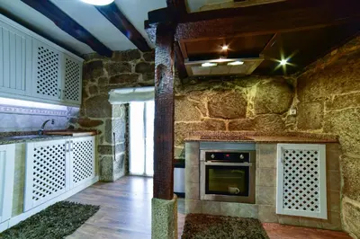 a kitchen with a stone wall and a stove at Casa da Xeitosa in Barbudo