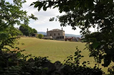 a large grassy field with a house in the background at Las Horas Perdidas in Moscán