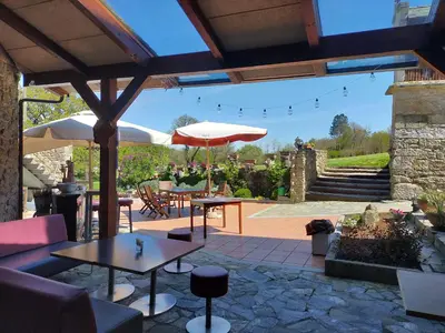 a patio with tables and umbrellas and a stone wall at Las Horas Perdidas in Moscán