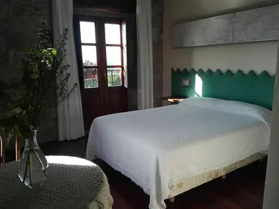a bedroom with a large white bed with a green headboard at Las Horas Perdidas in Moscán
