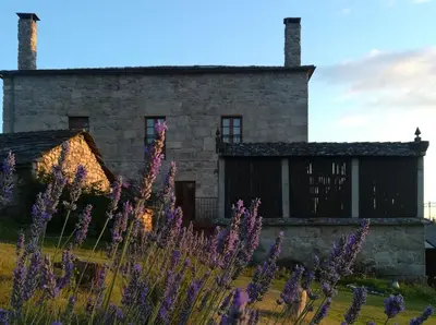 an old stone house with purple flowers in front of it at Las Horas Perdidas in Moscán