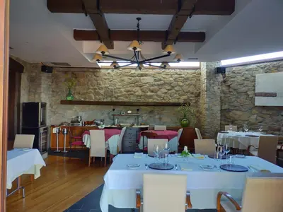 a restaurant with white tables and chairs and a stone wall at Las Horas Perdidas in Moscán
