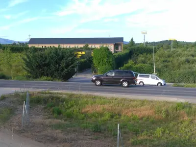 two cars parked on a road in front of a building at Motel Acropolis in Camponaraya