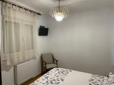a bedroom with a bed and a chandelier and a chair at Apartamento Vistas al mar in Foz