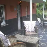 a porch with two chairs and a table and a couch at Apartamentos Los Balcones in Tineo