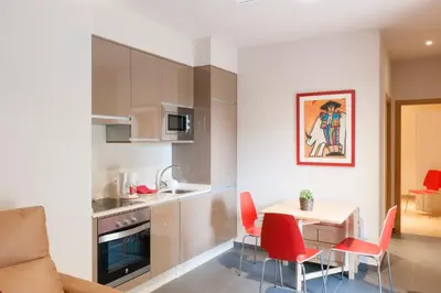 a kitchen and dining room with a table and red chairs at Apartamentos Rurales Los Mazos in Boal