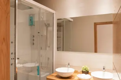 a bathroom with two sinks and a shower at Apartamentos Rurales Los Mazos in Boal