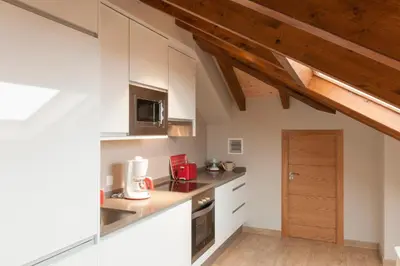 a kitchen with white cabinets and a wooden ceiling at Apartamentos Rurales Los Mazos in Boal
