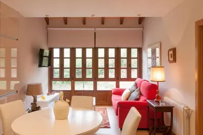 a living room with a red couch and a table at Apartamentos Rurales Los Mazos in Boal