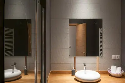two sinks in a bathroom with two mirrors at Apartamentos Rurales Los Mazos in Boal