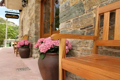 a wooden bench sitting next to a building with flowers at Casa Lixa Hotel Rural Albergue in Las Herrerías