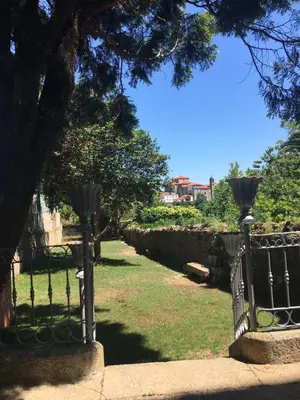 a wrought iron fence in a park with a tree at Pensión O Xardin de Julia in Santiago de Compostela