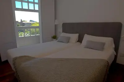 a large white bed in a room with a window at Pensión O Xardin de Julia in Santiago de Compostela