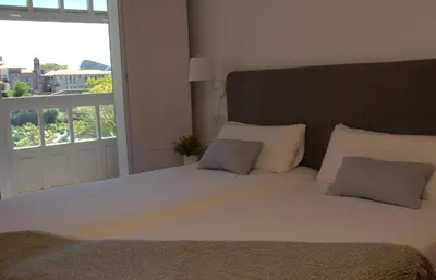 a bedroom with a large bed with a large window at Pensión O Xardin de Julia in Santiago de Compostela
