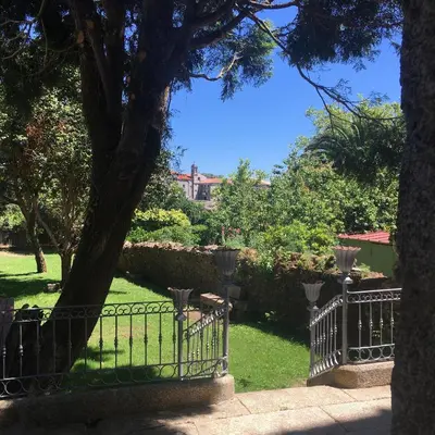 a wrought iron fence in a yard with a tree at Pensión O Xardin de Julia in Santiago de Compostela