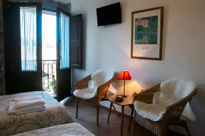 a room with a bed and chairs and a table at Posada El Tesin in Rabanal del Camino