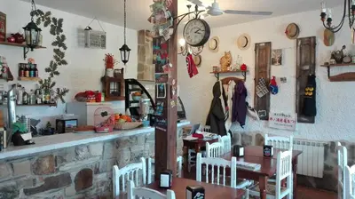 a restaurant with a table and a clock on the wall at Posada El Tesin in Rabanal del Camino